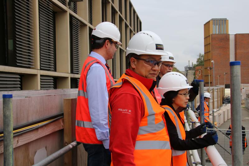 Andy Fong and Dr May Chan stood wearing high-visibility jackets and hardhats at the Stephen A Schwarzman Centre for the Humanities building site
