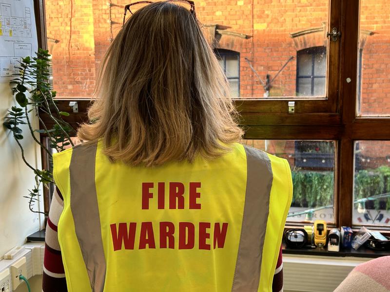 Jo Wilby wearing high-vis fire warden jacket with her back to the camera